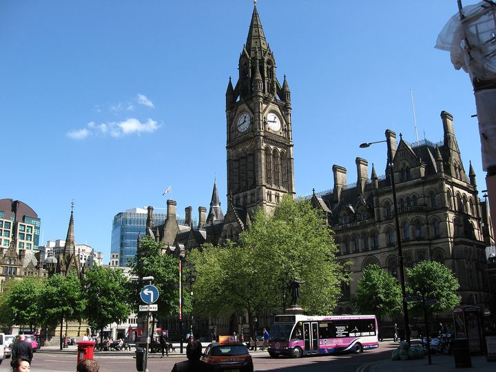 Manchester Town Hall and its clock tower above Albert Square on a sunny day.